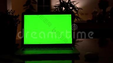 在客厅的办公桌上展示绿色彩色钥匙屏幕的笔记本电脑。 在后台舒适的客厅里